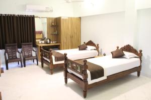1 dormitorio con 2 camas, mesa y sillas en Indian Residency en Tiruchchirāppalli