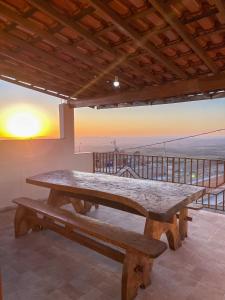 uma grande mesa de piquenique em madeira numa varanda com um pôr-do-sol em Casa Por do Sol. em São Tomé das Letras