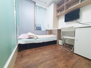 um pequeno dormitório com uma cama e uma televisão em Apgujeong Home em Seul