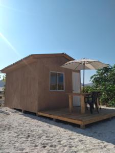 Cabaña pequeña con mesa y sombrilla en Portofino Surf Camp en Chañaral