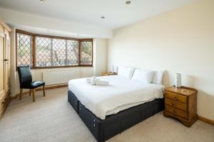 a bedroom with a large bed and a chair at Elegant 2BD House with Garden and Decked Patio in London