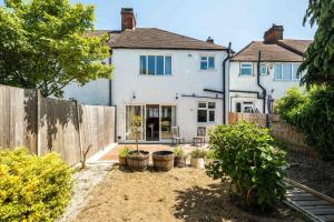 a house with a fence in front of a yard at Elegant 2BD House with Garden and Decked Patio in London
