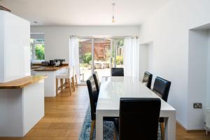 a kitchen and dining room with a white table and chairs at Elegant 2BD House with Garden and Decked Patio in London