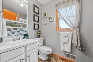 a bathroom with a toilet and a sink and a window at LONG LAKE RETREAT- Hot tub, Pool table, Firepit in Traverse City +56 photos
