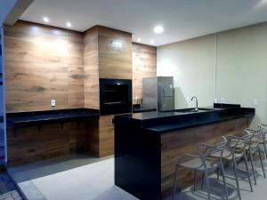 a kitchen with a black counter and some chairs at Apto novo Parque Mosaico in Manaus