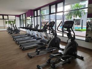 eine Reihe von Kardiogeräten in einem Fitnessraum mit Fenstern in der Unterkunft Alpine Conezion Golf View Netflix at IOI City Mall in Putrajaya