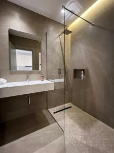 een badkamer met douche, wastafel en spiegel bij Skanderbeg Center Apartments 1 in Tirana