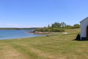 una casa sentada al lado de un campo junto a un lago en Point Field en Deer Isle