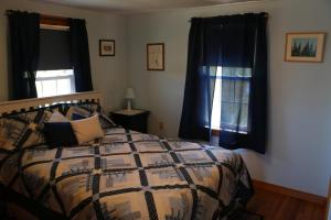 1 dormitorio con 1 cama con edredón y 2 ventanas en Point Field en Deer Isle