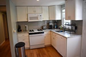 a kitchen with white cabinets and a white stove top oven at Seaside Serenity, just a block /0.1 mile away from the beach in Yarmouth