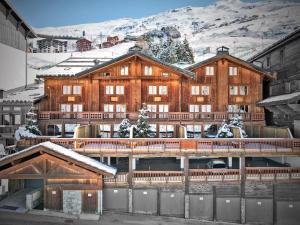 un grande edificio in legno con una montagna innevata di Chalet familial 12 pers avec jacuzzi et ski-in/ski-out - FR-1-613B-40 a Les Bruyères