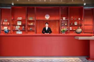 un hombre de traje sentado en un mostrador rojo en RiZhao Mumian Hotel, en Rizhao