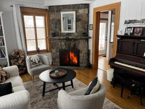 a living room with a fireplace and a piano at Auberge musicale Pour un Instant in La Malbaie