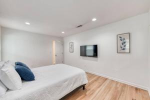 a white bedroom with a bed and a flat screen tv at The Happy Hideaway 1BR Unit in Fresno