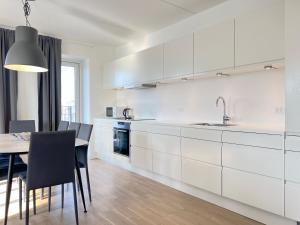 una cocina con armarios blancos y una mesa con sillas. en Modern Spacious 3 Bedroom Apartment At Ricahrd Mortensens Vej With Balcony Close To The Royal Arena And Fields en Copenhague