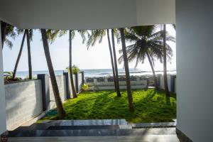 - une vue sur la plage depuis une maison avec des palmiers dans l'établissement Reunion Ocean Manor - Beach House, à Udupi