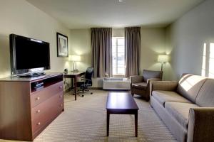 Cobblestone Inn & Suites-Winterset في Winterset: غرفة معيشة مع أريكة وتلفزيون بشاشة مسطحة