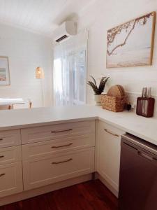 a kitchen with white cabinets and a window at Port Douglas Beach Cottage in Port Douglas +26 photos