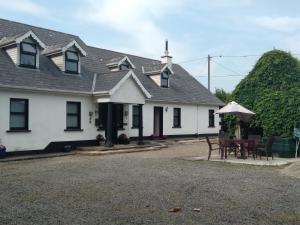 a white house with a table and an umbrella at Dunroven Guest House in Carlow