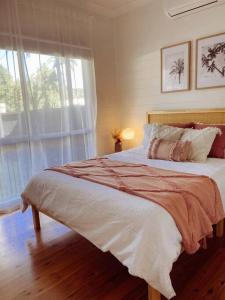 a bedroom with a large bed and a window at Port Douglas Beach Cottage in Port Douglas