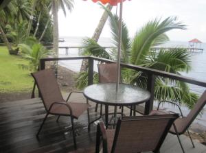 einen Tisch und Stühle auf einer Terrasse mit Meerblick in der Unterkunft Pension Reva Teahupoo in Toanoano