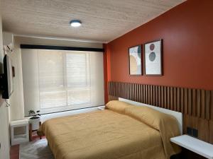 - une chambre avec un lit aux murs orange et une fenêtre dans l'établissement Xochimilco Apartment, à Oaxaca