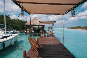 un muelle con sillas en un barco en el agua en Bluebayou Bacalar en Bacalar