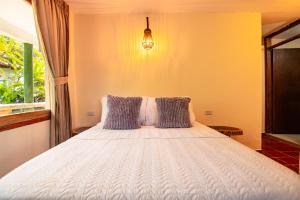 een slaapkamer met een wit bed met kussens en een raam bij Portales del Tayrona Garden Hotel in Calabazo