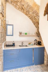 eine Küche mit blauen Schränken und einer Steinmauer in der Unterkunft Napoleon with rooftop terrace in Akkon