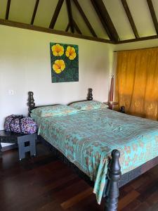 1 dormitorio con 1 cama y una pintura en la pared en Pension Reva Teahupoo, en Toanoano