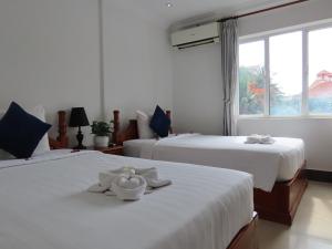 a bedroom with two beds with white sheets and a window at The Blanc Residence in Siem Reap