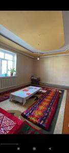 Guest house В гостях у Лаззат في Türkistan: غرفة مع طاولة وبعض البطانيات الملونة