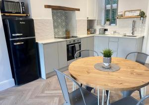 a kitchen with a wooden table and a black refrigerator at ‘Sandy Bottom’ - Apartment by the sea in Combe Martin