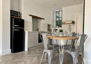 cocina con mesa, sillas y nevera negra en ‘Sandy Bottom’ - Apartment by the sea, en Combe Martin