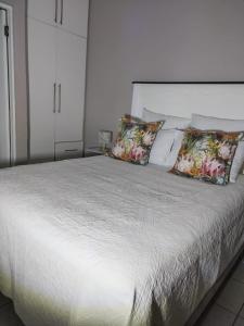una camera con letto bianco e cuscini di 19 Mirabelle Place a Pietermaritzburg