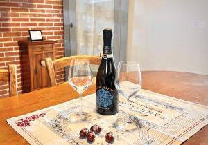 una bottiglia di vino seduta su un tavolo con due bicchieri da vino di Boutique House Alle Loggie Palladiane di Villa Contarini a Piazzola sul Brenta
