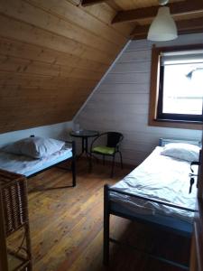 ベトリナにあるWiklinowa Zatokaのベッド2台、テーブル、窓が備わる客室です。