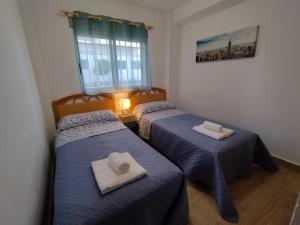 2 camas en una habitación con sábanas azules y toallas en Living Benidorm. Playa Levante, en Benidorm