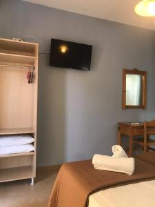 a bedroom with a bed and a tv on the wall at Tasos Rooms in Prinos