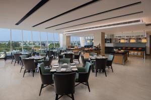 un comedor con mesas, sillas y ventanas en Fairfield by Marriott Agra en Agra