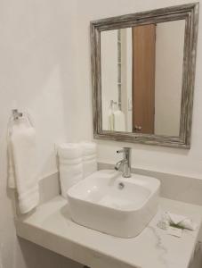 a bathroom with a sink and a mirror and towels at Hotel La Lejona in San Miguel de Allende