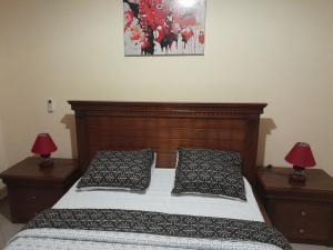 un letto con due cuscini e una foto sul muro di Lydie's Home a Yaoundé