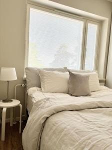 Una cama con almohadas y una ventana en un dormitorio. en Puumaja Penthouse en Rauma