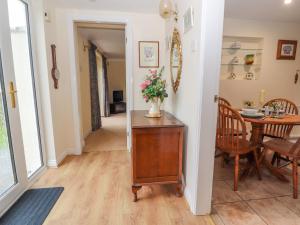 een woonkamer met een tafel en een vaas met bloemen op een kast bij Bryn Offa cottage in Holywell