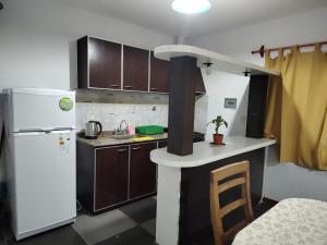 una pequeña cocina con nevera blanca y armarios marrones en D&D alojamiento en Guaymallén