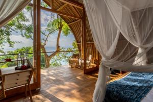 a bedroom with a canopy bed and a balcony at Morin Resort in Nusa Lembongan
