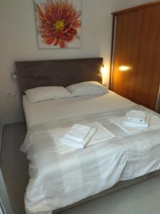 a white bed with two towels on top of it at Orchid SeaView Apartment With Garage Parking in Zaton