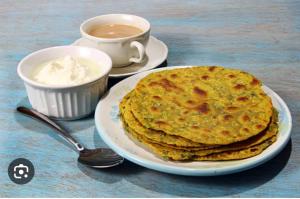 a stack of pancakes on a plate next to a cup of coffee at Sufi Khandar Home Stay in New Delhi