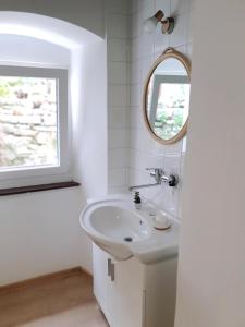 a white bathroom with a sink and a mirror at Holiday Home Dunja in Opatija