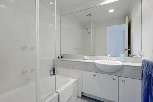 a white bathroom with a sink and a mirror at Spacious apartment minutes from the CBD in Melbourne